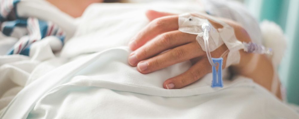 a woman laying in a hospital bed with an iv in her hand